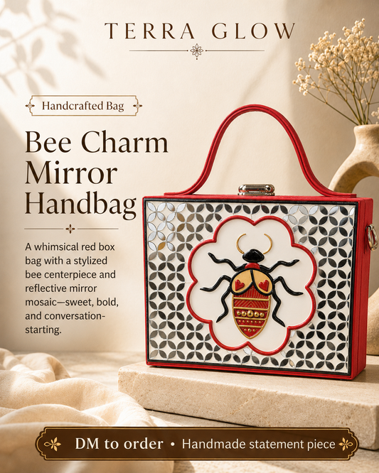 Terra Glow Bee Charm Mirror Handbag in red, featuring a white and black geometric mirror mosaic pattern with a central stylized bee charm on a flower-shaped frame, displayed on a stone pedestal with dried flowers in the background.